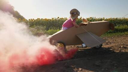 Dad rolls the child in a cardboard plane while walking down a country road on a sunny day