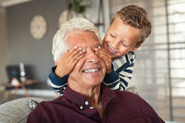 Playful little boy covering grandpa's eyes