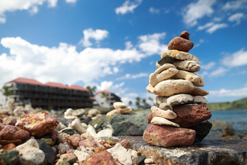 Stones balance on beach and behind hotel resort in blur 