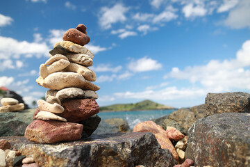 Fototapeta na wymiar Stones balance on beach and behind hotel resort in blur 