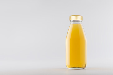 Yellow apple juice in glass bottle with gold cap  mock up on white background with copy space,...