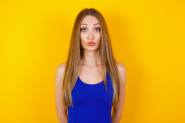 Attractive light haired female rounds lips, wears casual clothes, looks directly into camera,...