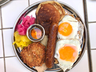 American Breakfast with Pancake Maple Syrup, Sunny Side Up Eggs, Hash Brown, Sausage, Turmeric Pickled Onions and Pickle.