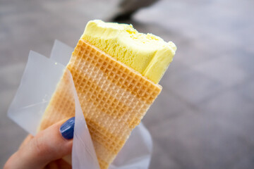 Durian Ice Cream in a waffle in a woman's hand, made of Durian (Durio), asian fruit having strong,...
