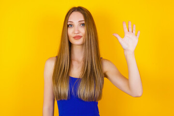 Fototapeta premium Young woman standing against gray wall showing and pointing up with fingers number five while smiling confident and happy.