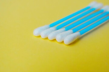 Ear cotton buds are blue on a yellow background. Cosmetology and medicine. Personal hygiene and care.