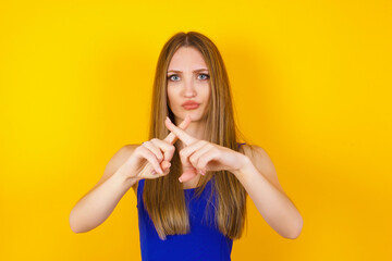 Fototapeta premium Young beautiful brunette girl wearing casual clothes over isolated background standing against gray wall. Has rejection angry expression crossing fingers doing negative sign.