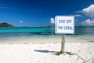 on wood board sign stay off the coralson the beautiful beach with colorful clear water in Caribbean sea   