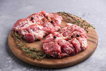 Fresh raw pork chop meat on wooden cutting board with spices