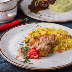 Baked chicken fillet and rice with vegetables on a plate.