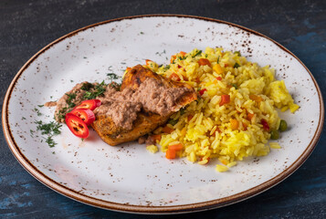 Chicken fillet and rice with vegetables on a plate.