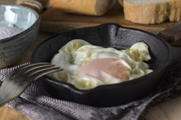 Huevo frito en una sartén antigua de hierro colada, junto con un poco de pan y sal, listo para comer. Concepto vintage