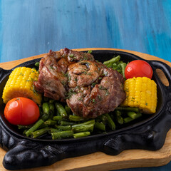 Fried pork with vegetables on frying pan. Closeup