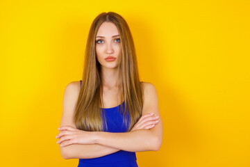 Picture of angry young beautiful woman standing isolated over bright background. Looking camera.