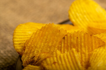 Fluted potato chips on a background of homespun fabric with a rough texture. Close up.