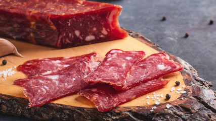 Delicious sliced salami on wooden cutting board. Macro view
