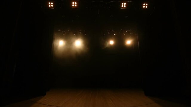 Strobing of yellow lghts on empty black stage.