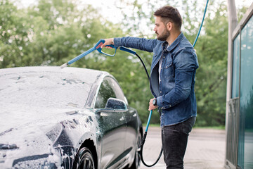 Washing of electric modern car on open air self car wash service with foam and high powered hose....