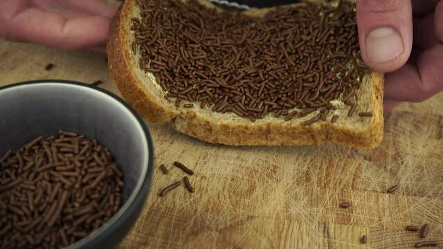 A typical dutch breakfast with a sandwich sprinkled with chocolate sprinkles. Taking a bite in slow motion
