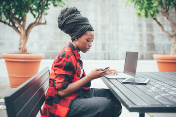 black woman freelancer working outdoor using smartphone, notebook and tablet - Multietasking female student using devices - learning, technology, business concept