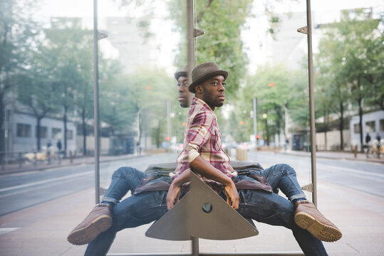 Blak man sitting bus stop - Black male waiting public transport - commuting, travelling, transportation concept