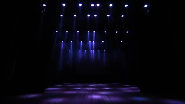 Many lighting devices on the empty stage of the concert hall.