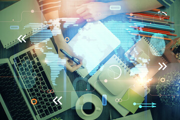 Double exposure of hands making notes with world map hologram and data theme icons. Concept of international network data.