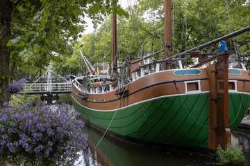 City of Papenburg Germany. Canal and flowers. Bridge and old boat. Sailingship.