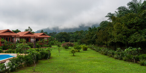 Fototapeta na wymiar From the cabins and garden (left) tourists have a breathtaking view to the Khao Sok jungle and nearby mountains. This morning during the rainy season, though, the dense fog is covering them.