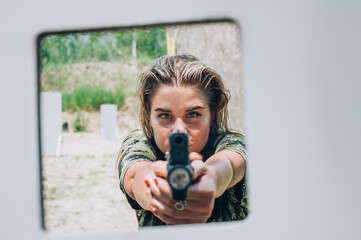 Close-up abstract view of attractive female army soldier have gun shooting training from behind and around cover or barricade. Advanced fighting tactical shooting courses on shooting range