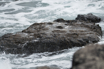 Naklejka premium Waves crashing against rocks at the Giant's Causeway, Northern Ireland.