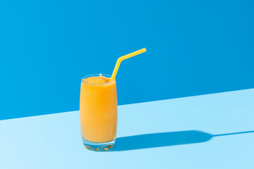 Mango smoothie on blue color. Summer drink. Mango shake with a straw