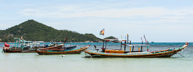 Fototapeta na wymiar Characteristic Asian fishing boats are a part of many smaller beach sites in Thailand, as they provide food for both locals and restaurants. These are in a scenic beach view at Koh Tao, Thailand