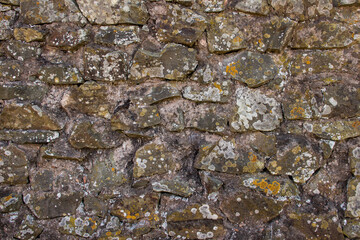Close-up of masonry on an old stone wall covered with moss.