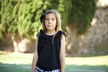 Fototapeta premium Photo of amazed puzzled little girl with ginger hair knot, curves lips and has worried look, sees something awful in front.