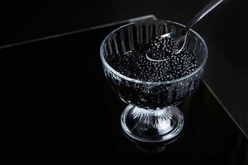 Black sturgeon caviar in a glass jar, on a dark background. Expensive delicacies. Healthy food.