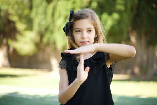 Young pretty blonde girl tired and bored, making a timeout gesture, needs to stop because of work stress, time concept. Standing against gray wall.
