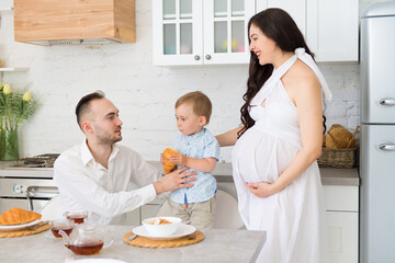 happy family in home kitchen married couple with a small child and pregnant woman