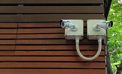 CCTV camera installed outdoor on a wooden wall  white green background. Security concept.