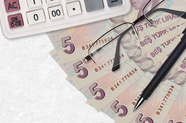 5 Turkish lira bills fan and calculator with glasses and pen. Business loan or tax payment season...
