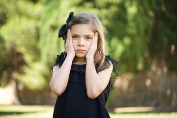 Portrait of beautiful young woman holding head in hands with unhappy expression watching sad movie about animals and trying not to cry.