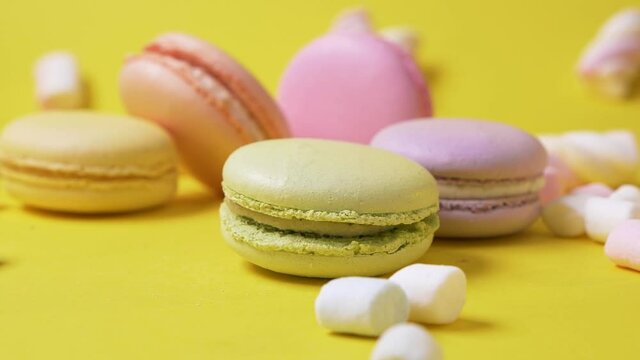 Slow motion macarone on yellow background to spin fall on table bakery food color sugar pearl french dessert delicious macaroon