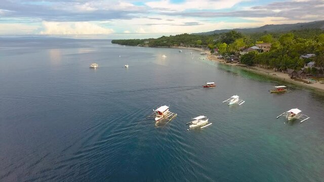 Aerial dolly forward view of a Bangka boat drifting on a bay from a village in Philippines, drone passin by shot