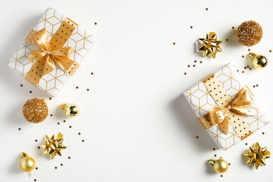 Happy New Year banner. Christmas design gold gifts box, golden balls, glitter confetti stars on white background. Decoration objects viewed from above.