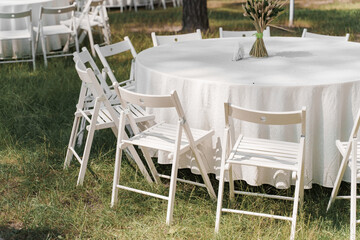 Table set up for wedding ceremony in the green forest. wedding chairs and covers at outdoor wedding