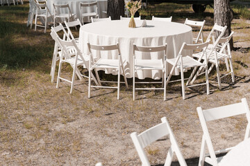 Table set up for wedding ceremony in the green forest. wedding chairs and covers at outdoor wedding