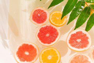 Orange, lemon, grapefruit fruits in the water with green leaves. Decoration for party, Citrus fruits in the bath at hot summer day. Fruits for cocktail