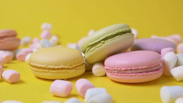 Close up marshmallow falls on macarone yellow background bakery food color sugar pearl french dessert delicious table macaroon slow motion