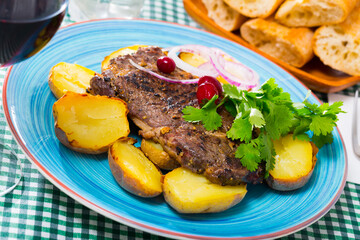 Juicy beefsteak served with baked potato and herbs on plate