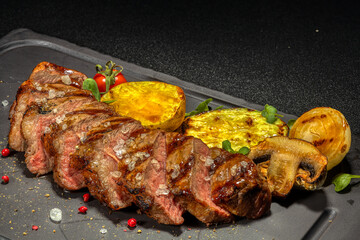 Steak with vegetables on a black plate